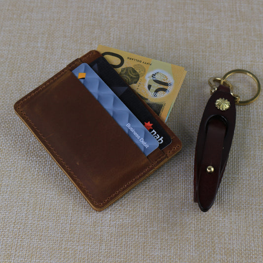 Slim handcrafted tan leather card wallet with a tiered pocket design, shown with NAB debit cards and a secure brass-hardware leather key fob.