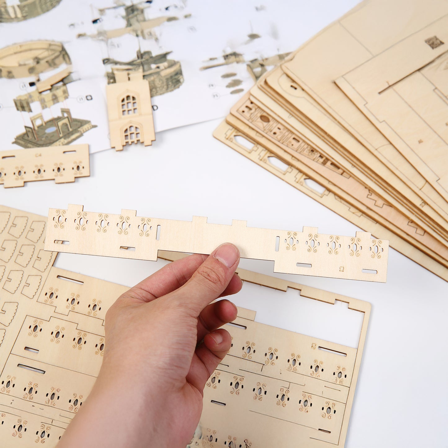 Wooden building blocks and a hand assembling them on a white surface