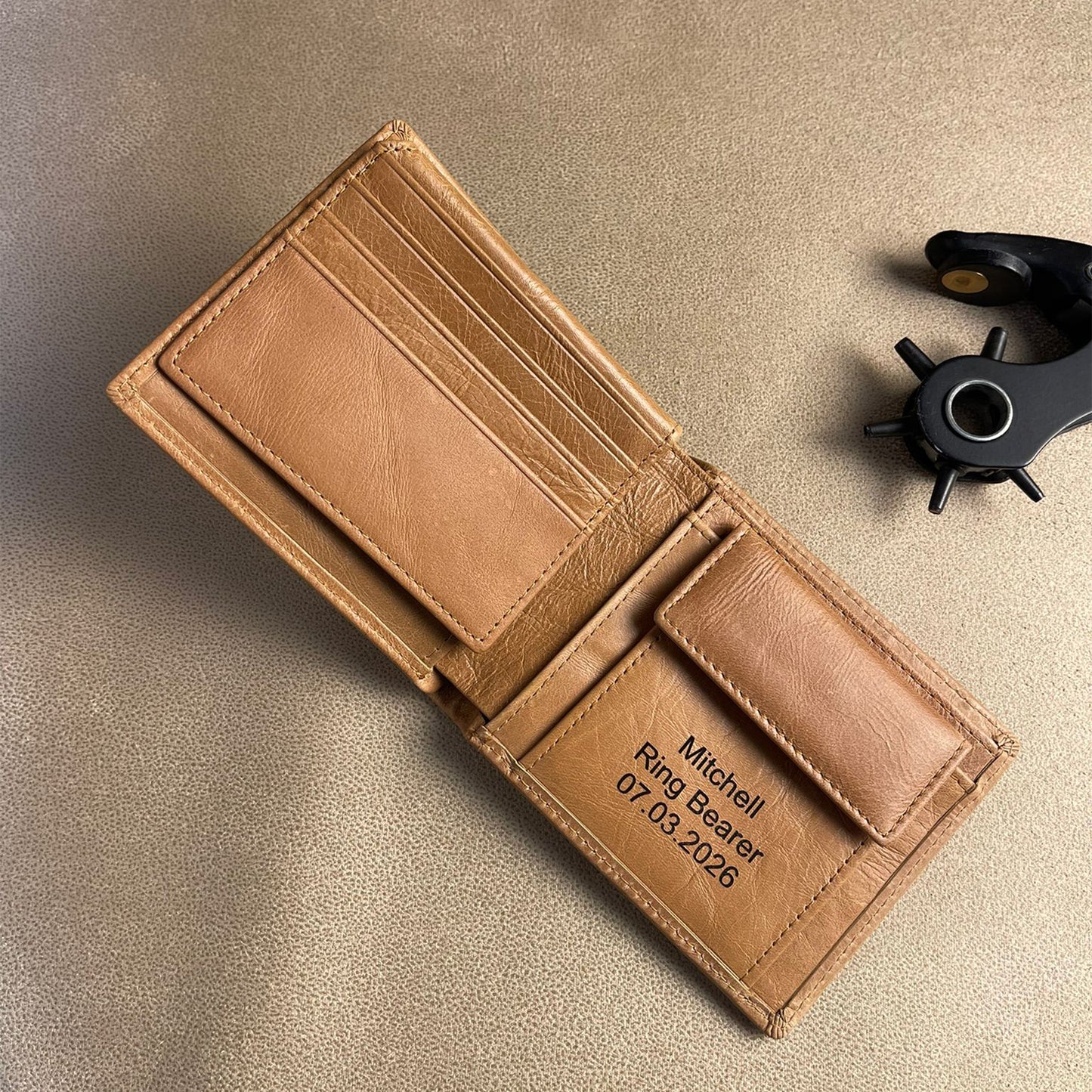 Brown leather wallet with engraved text on a beige surface
