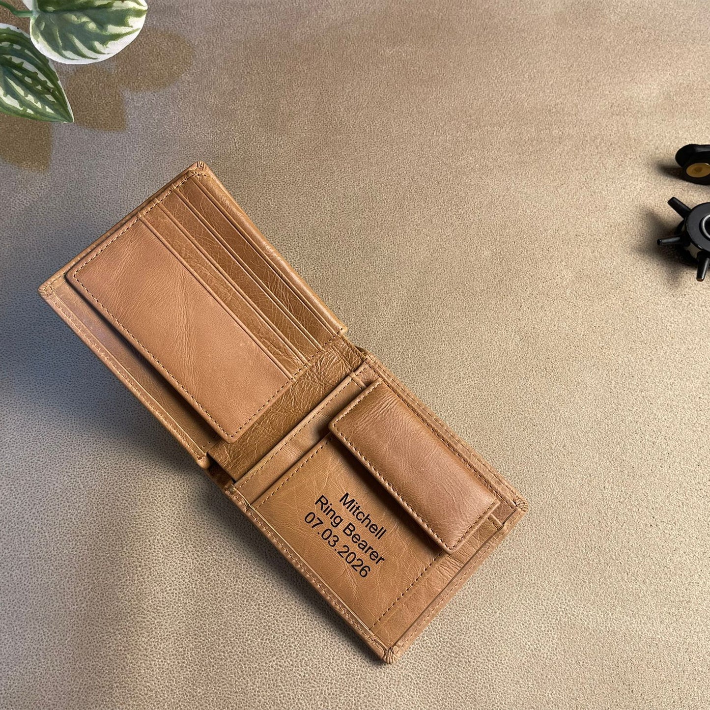 Brown leather wallet with engraved text on a beige surface