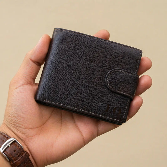 Leather Bifold Wallet in pebbled espresso leather held in hand, featuring custom initials and secure snap tab closure.
