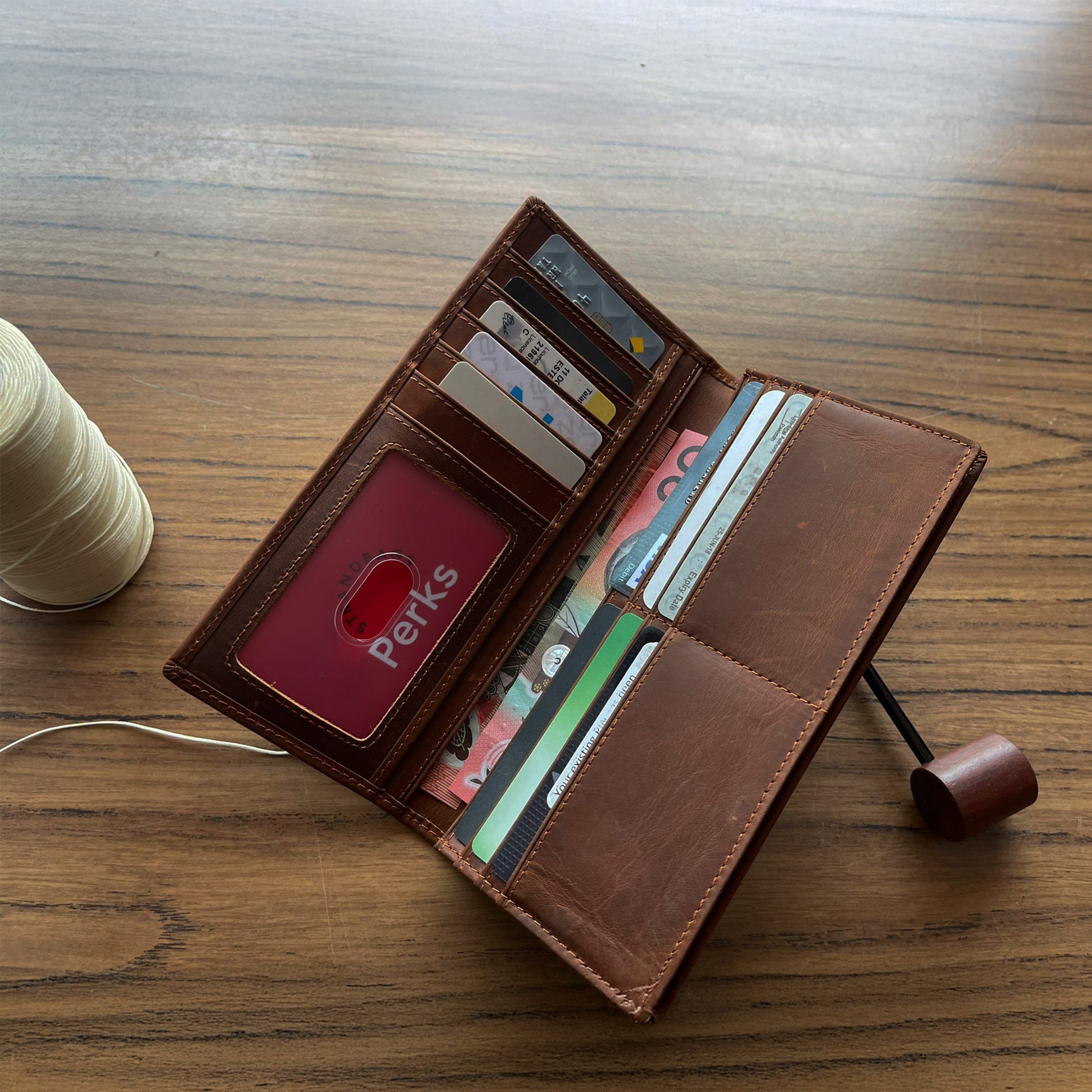 Handcrafted light brown leather trifold wallet for men, featuring high-capacity organized storage and durable hardware, presented on a rustic burlap surface.