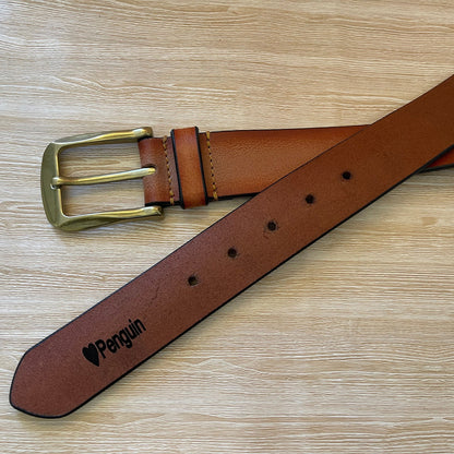 Brown leather belt with brass buckle on a wooden surface