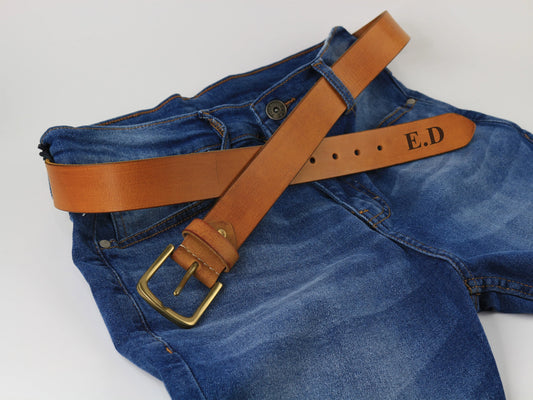 Blue jeans with a brown leather belt featuring initials on a white background