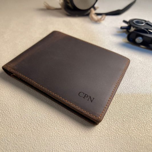 Brown leather wallet with 'CPN' initials on a light surface