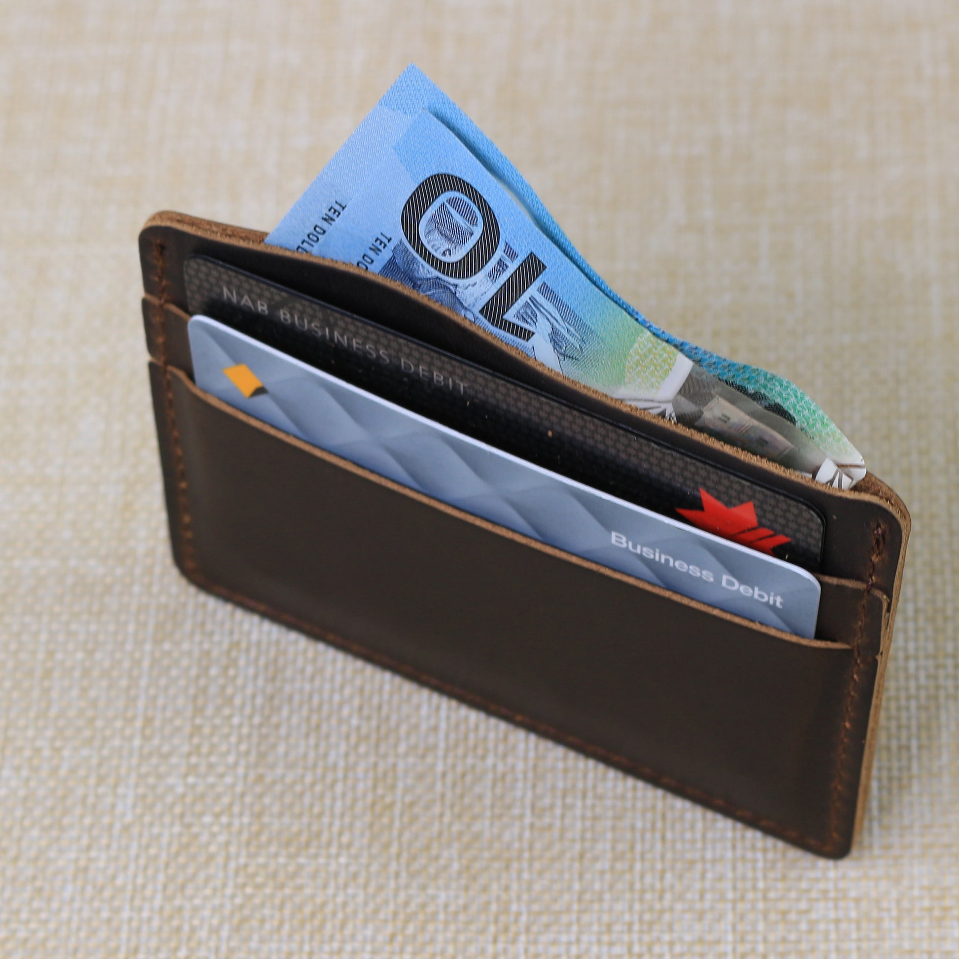 Ultra-slim handmade leather card holder sleeve demonstrating a low-profile design for front pocket carry.