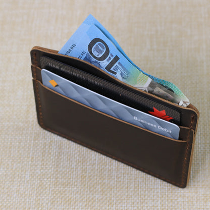Ultra-slim handmade leather card holder sleeve demonstrating a low-profile design for front pocket carry.