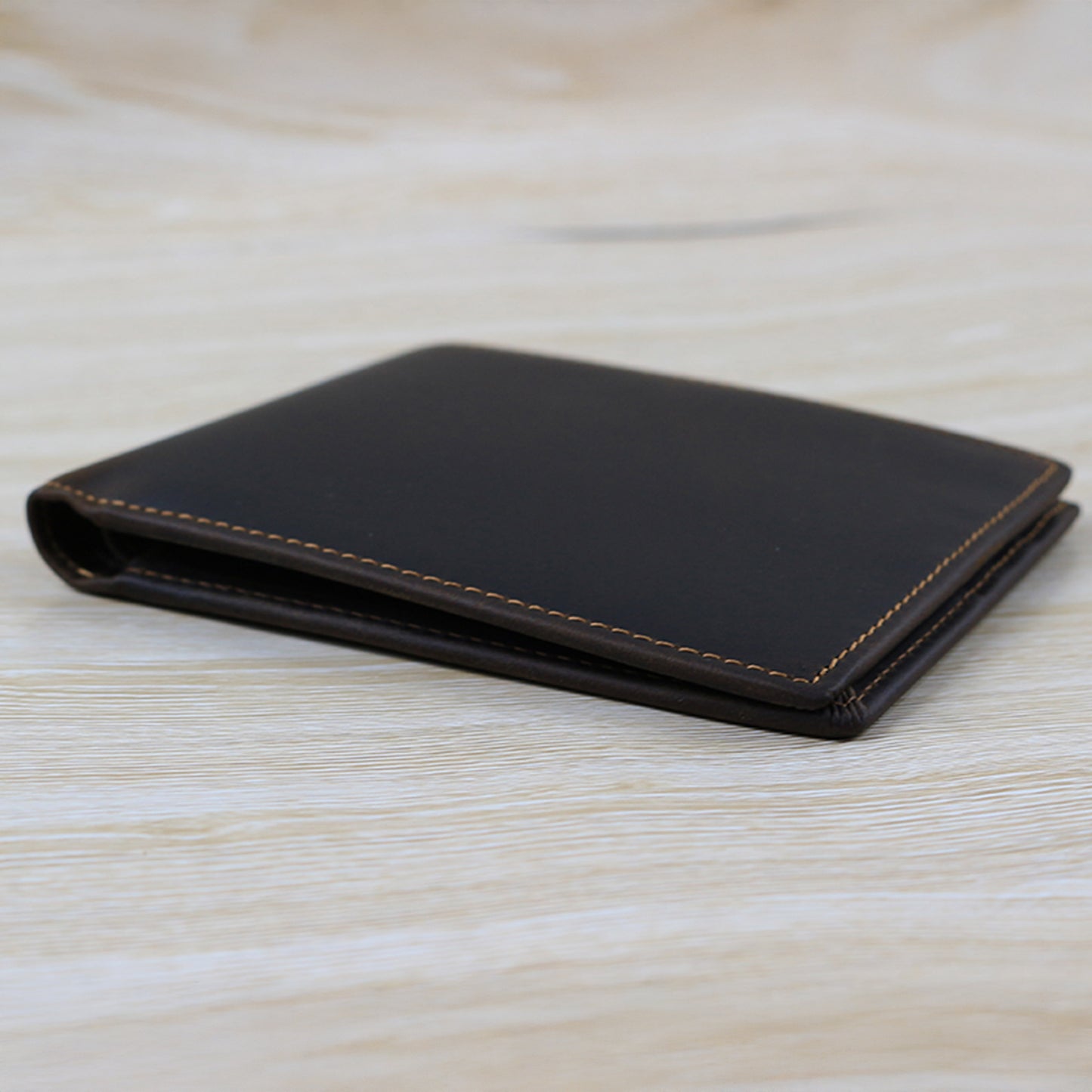 Black leather wallet on a light wooden surface