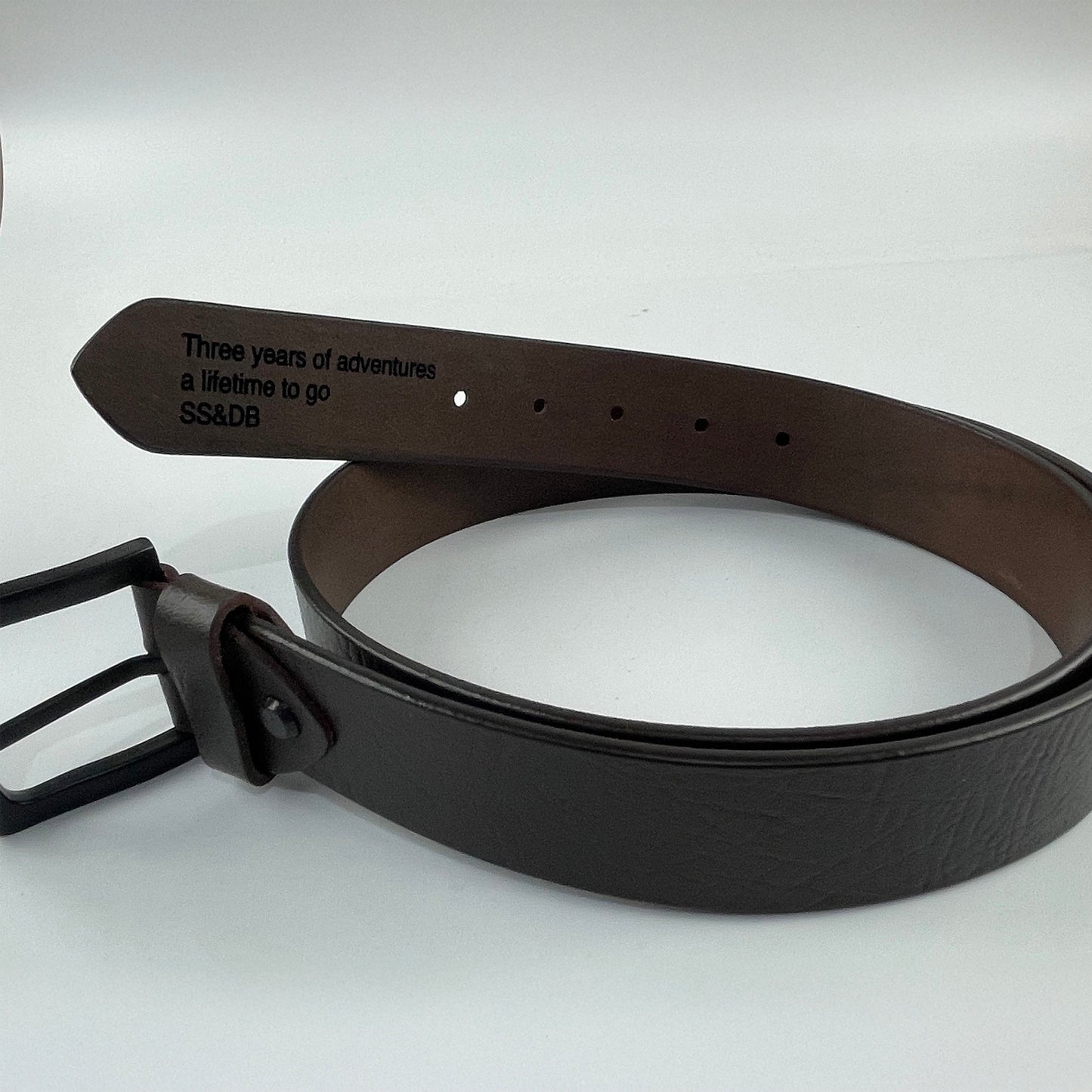 Brown leather belt with engraved text on a white background