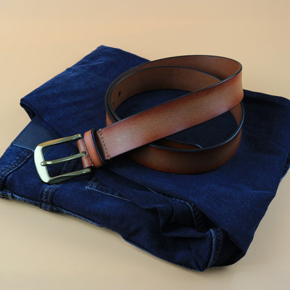 Brown belt with gold buckle on a folded blue denim shirt against a beige background