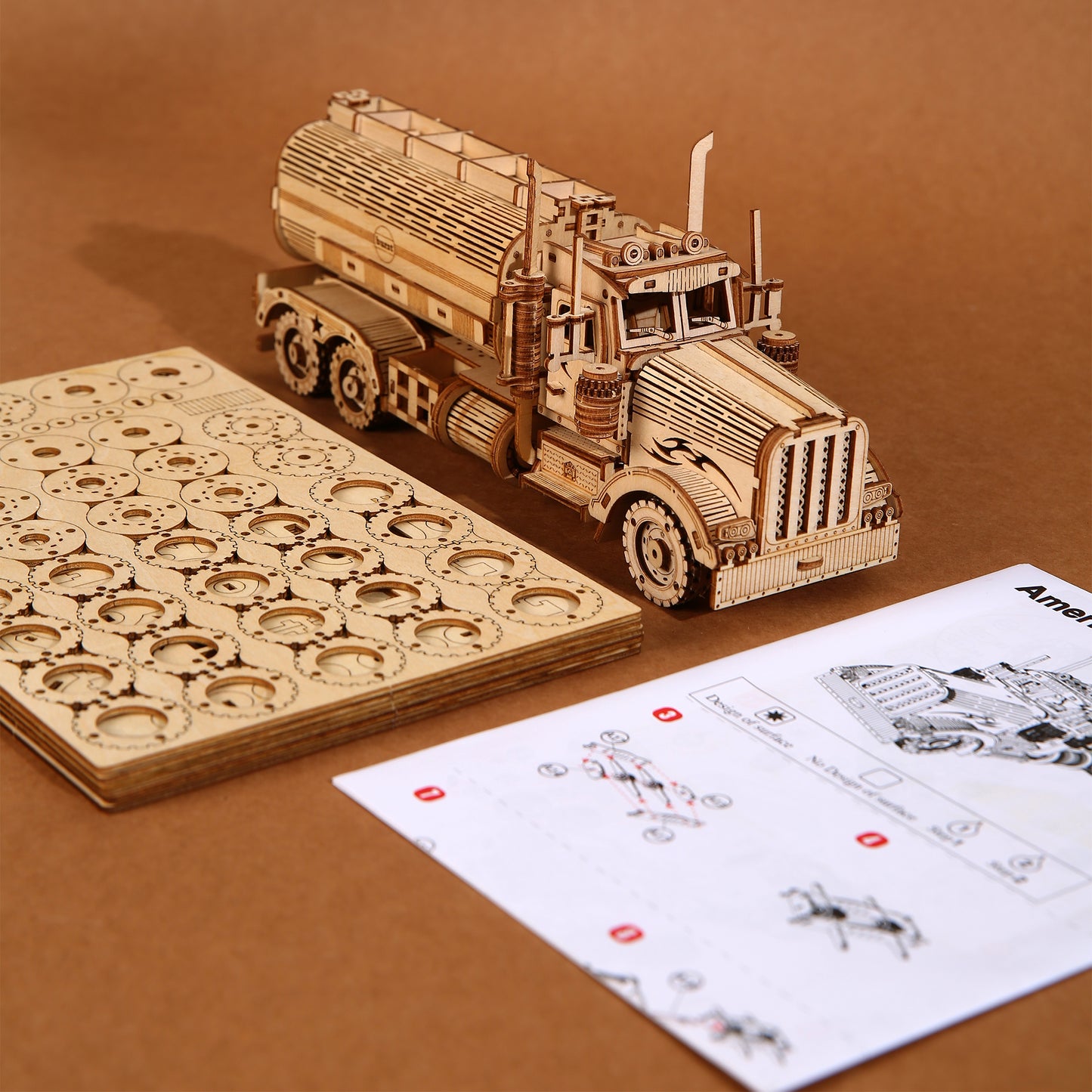 Wooden model truck kit with unassembled parts and instructions on a brown background