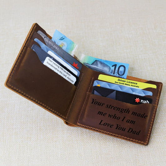 Open brown leather wallet with cards and money having engraved message inside placed on a beige fabric background