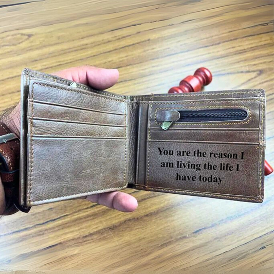 Brown leather wallet with engraved message inside, held by a hand on a wooden surface