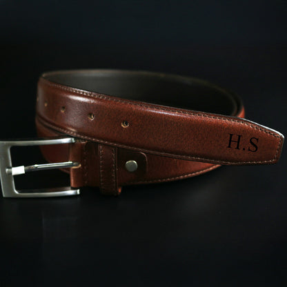 Brown leather belt with silver buckle on a black background