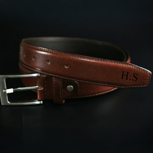 Brown leather belt with silver buckle on a black background
