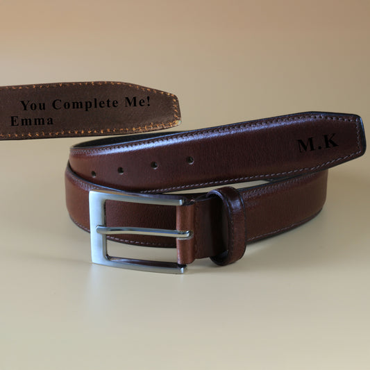 Brown leather belt with silver buckle on a beige background