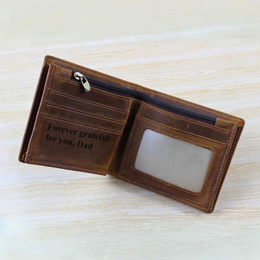 Brown leather wallet with engraved message on a light wooden surface