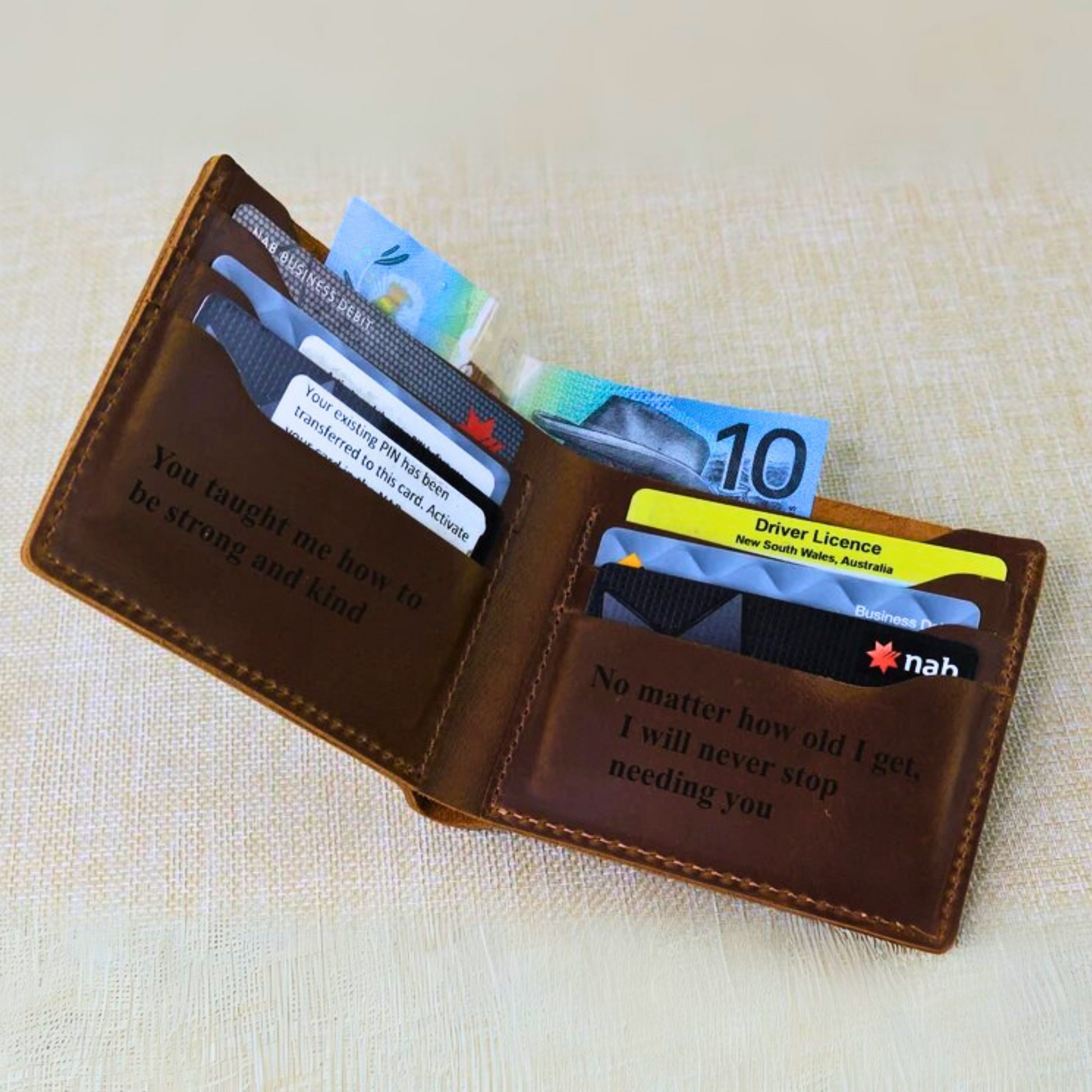 Brown leather wallet with cards and notes on a textured beige surface