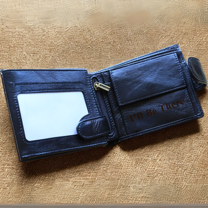 Black leather trifold wallet with 'I'll Be There' engraving on a beige textured surface