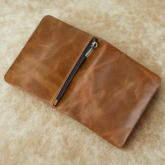 A zipped compartment on the back side of the Brown leather vertical wallet with a zipper on a beige surface
