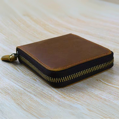 Brown and black zippered leather  wallet on a light wooden surface.