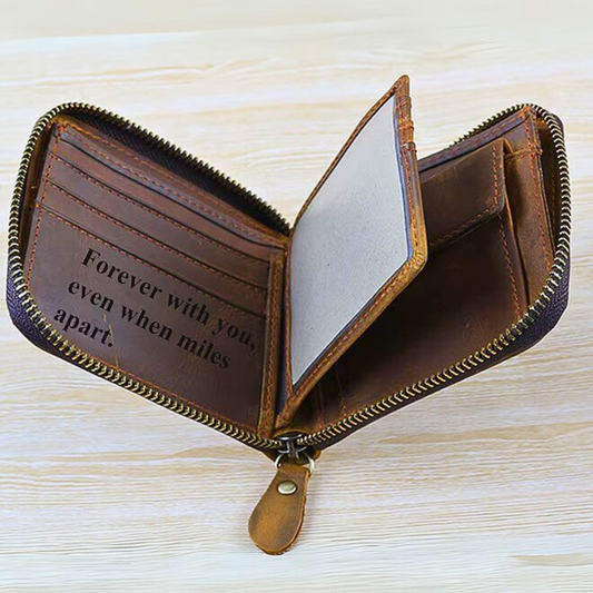 Brown leather zipper wallet with engraved message inside it,  on a light wooden surface