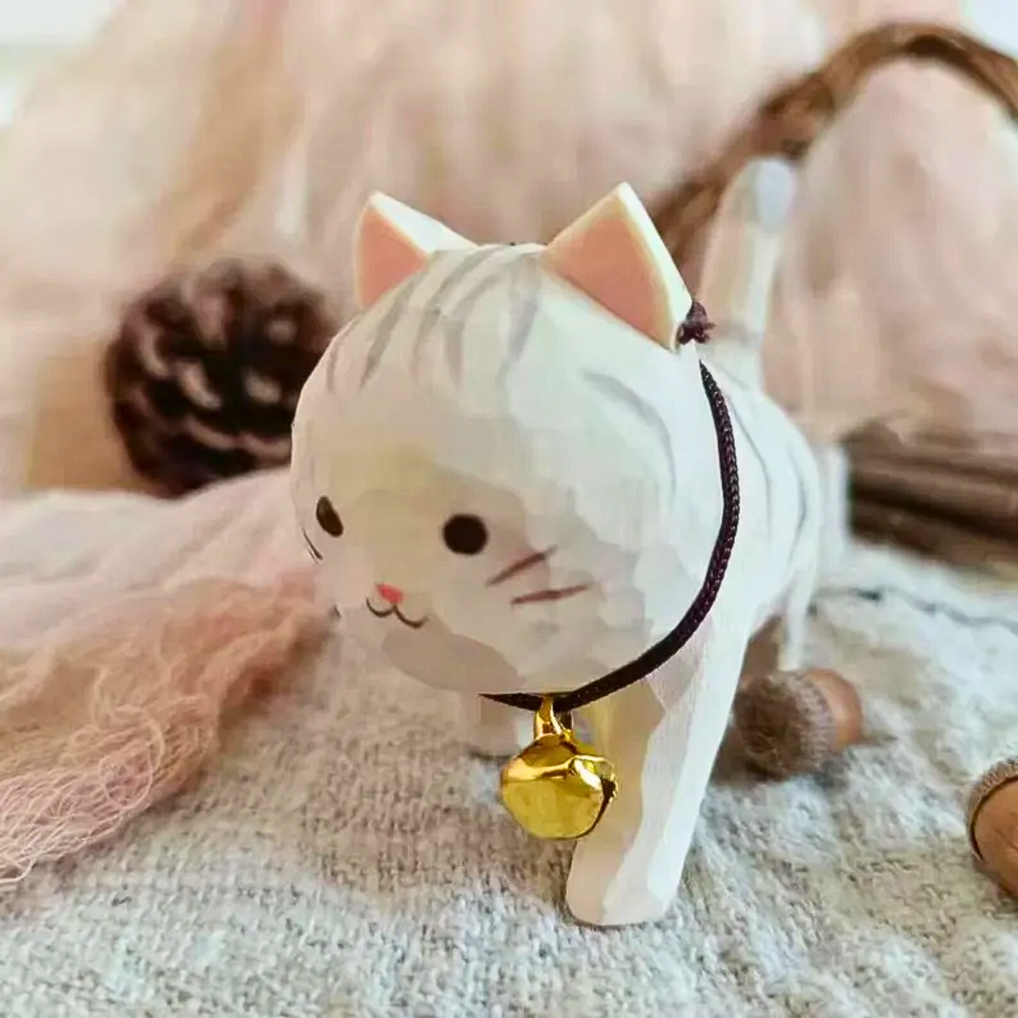 White cat figurine with a gold bell, hand carved and painted, used as a desk decor.
