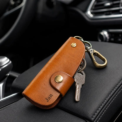 Personalised tan leather key holder engraved with James attached to car keys on vehicle centre console