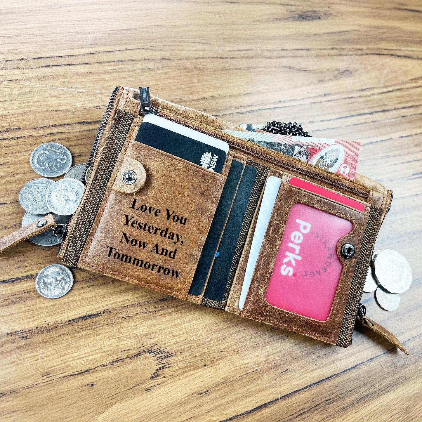 Custom engraved men's tan leather wallet with multiple card slots and ID window, shown with Australian coins as a personalized gift idea.