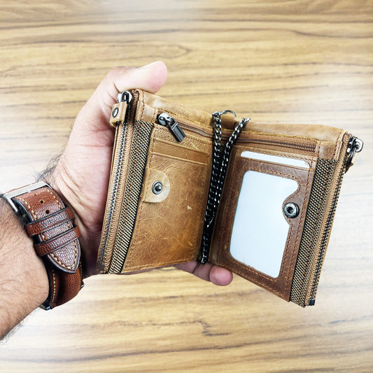 Brown leather wallet with chain held by a hand on a wooden surface