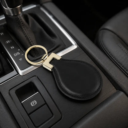 Black leather keychain with gold metal ring displayed beside car gear selector on vehicle centre console