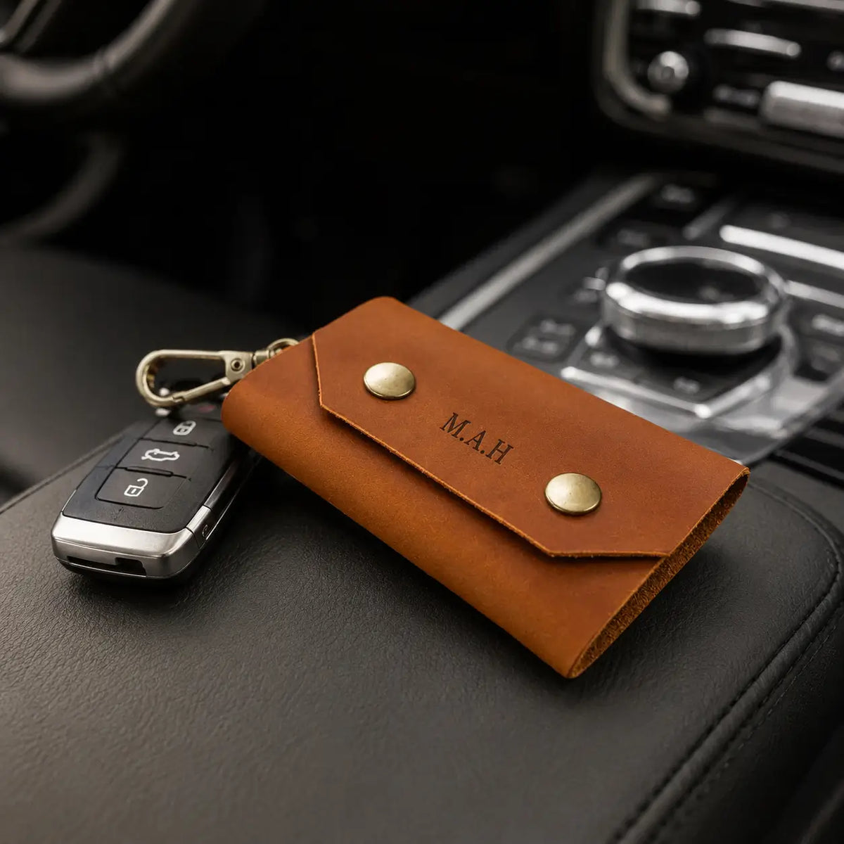 Tan leather key holder with attached car keys displayed on vehicle centre console