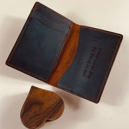 Interior view of a handmade leather wallet with multiple card slots and a custom engraved quote on full-grain brown leather.