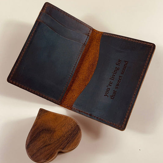 Interior view of a handmade leather wallet with multiple card slots and a custom engraved quote on full-grain brown leather.