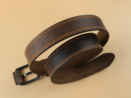 Brown leather belt with stitching on a beige background