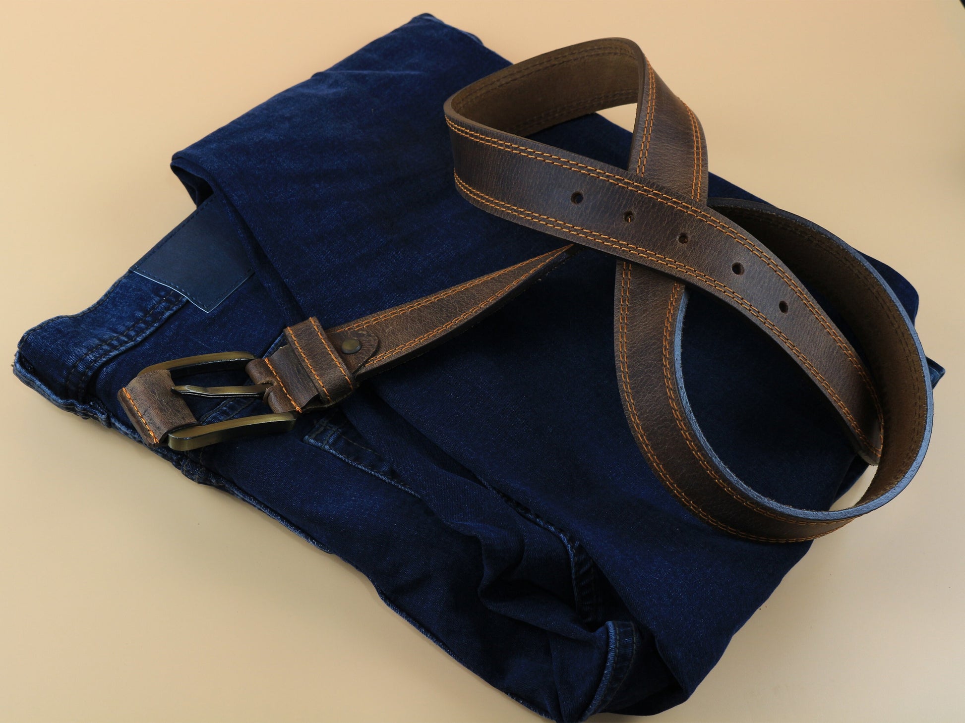Blue jeans with a brown belt on a beige background