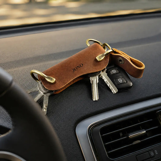 Personalised brown leather key holder with multiple keys and metal rings displayed inside a car