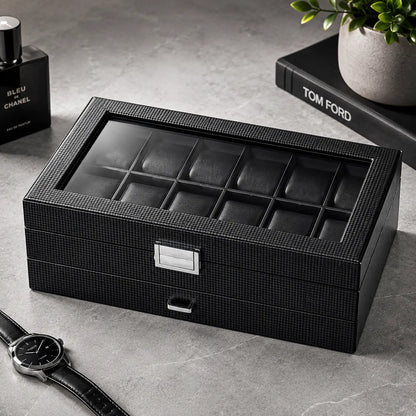 Closed carbon fiber men’s watch box with glass display lid and silver clasp placed on a modern grey stone surface beside luxury accessories, designer fragrance, and minimalist masculine décor.