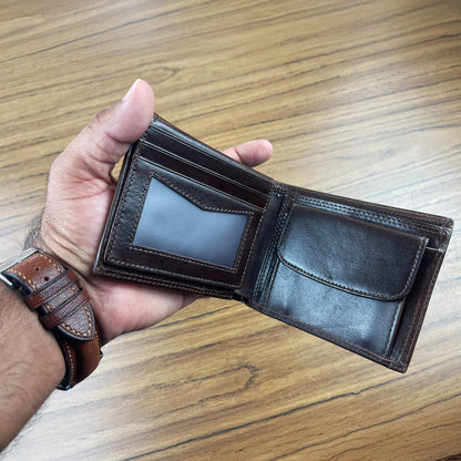 Hand holding an open brown leather wallet on a wooden surface