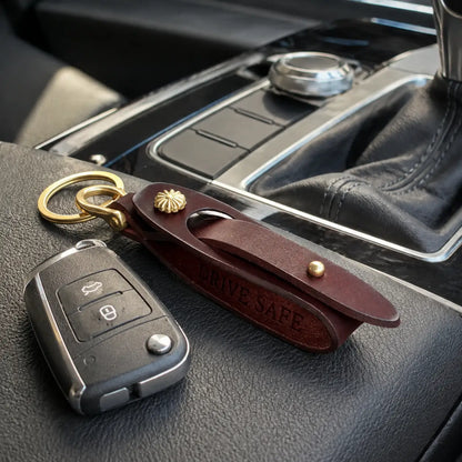 Brown leather key holder with attached car keys displayed on vehicle centre console
