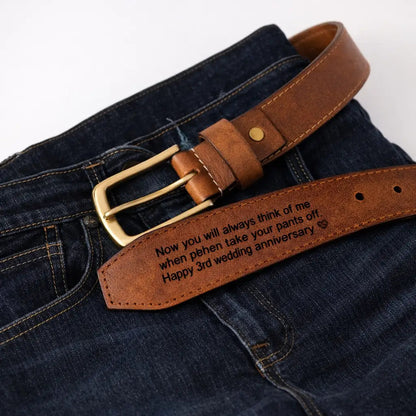 Custom engraved brown leather men’s belt with brass buckle styled over dark denim jeans, featuring a personalized anniversary message for husband gift ideas.