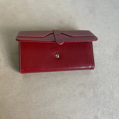 Burgundy red women’s wallet partially open showing snap closure, white stitching and leather-look finish