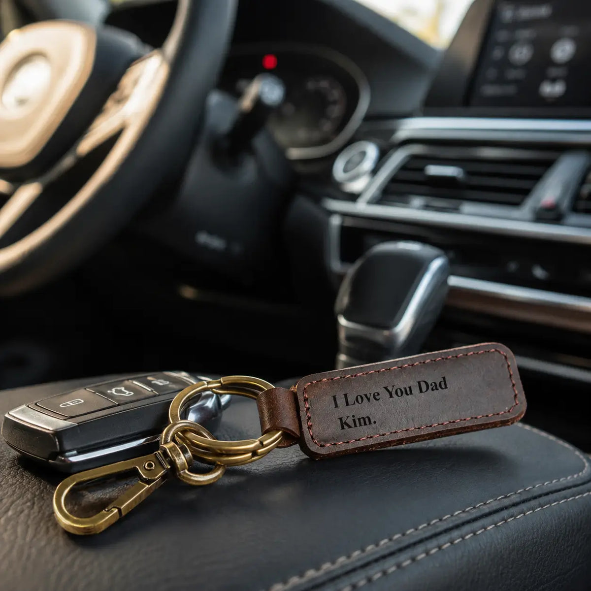 Personalised brown leather keychain attached to car keys and displayed on a vehicle seat
