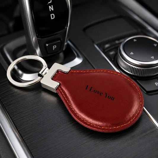Personalised brown leather keychain engraved with I Love You attached to car keys inside a vehicle