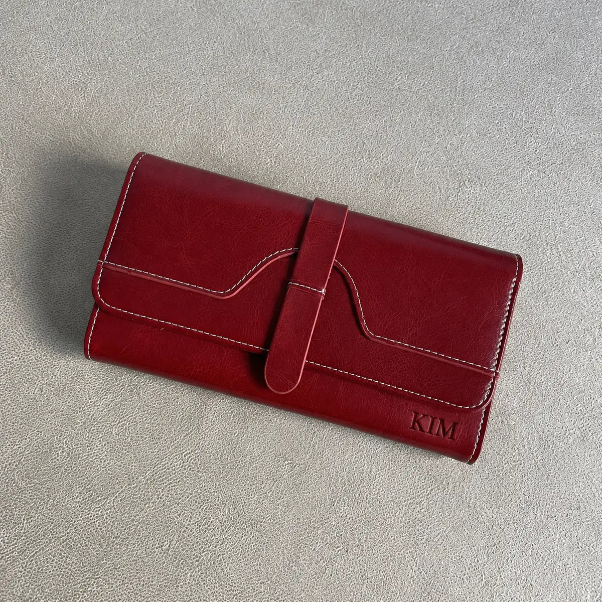 Personalised burgundy women’s wallet engraved with KIM featuring white stitching and front strap closure