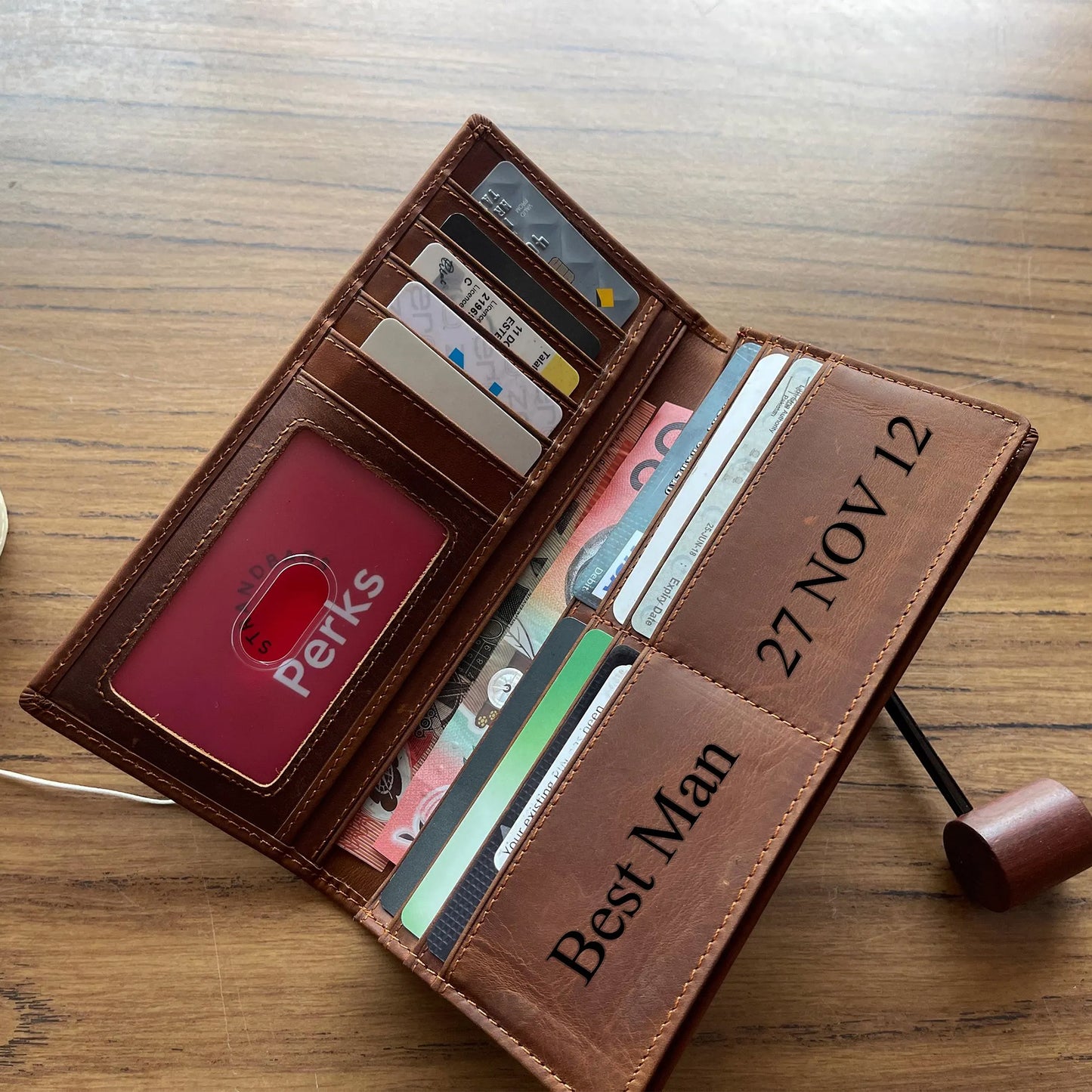 Handcrafted light brown leather trifold wallet for men, featuring high-capacity organized storage and durable metal hardware, presented on a rustic burlap surface.