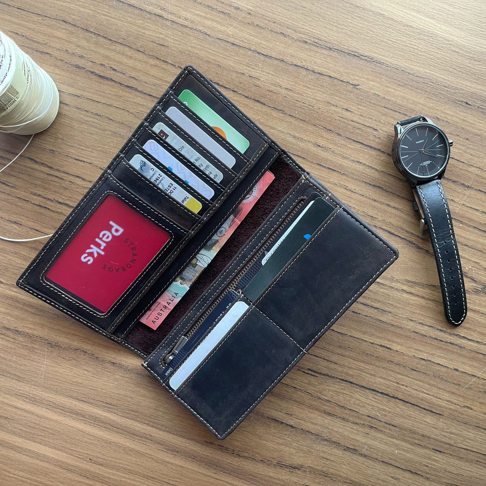 Slim black leather checkbook wallet for men with secure zipper compartment and ID holder, handcrafted leather travel organizer shown with bank cards and cash.