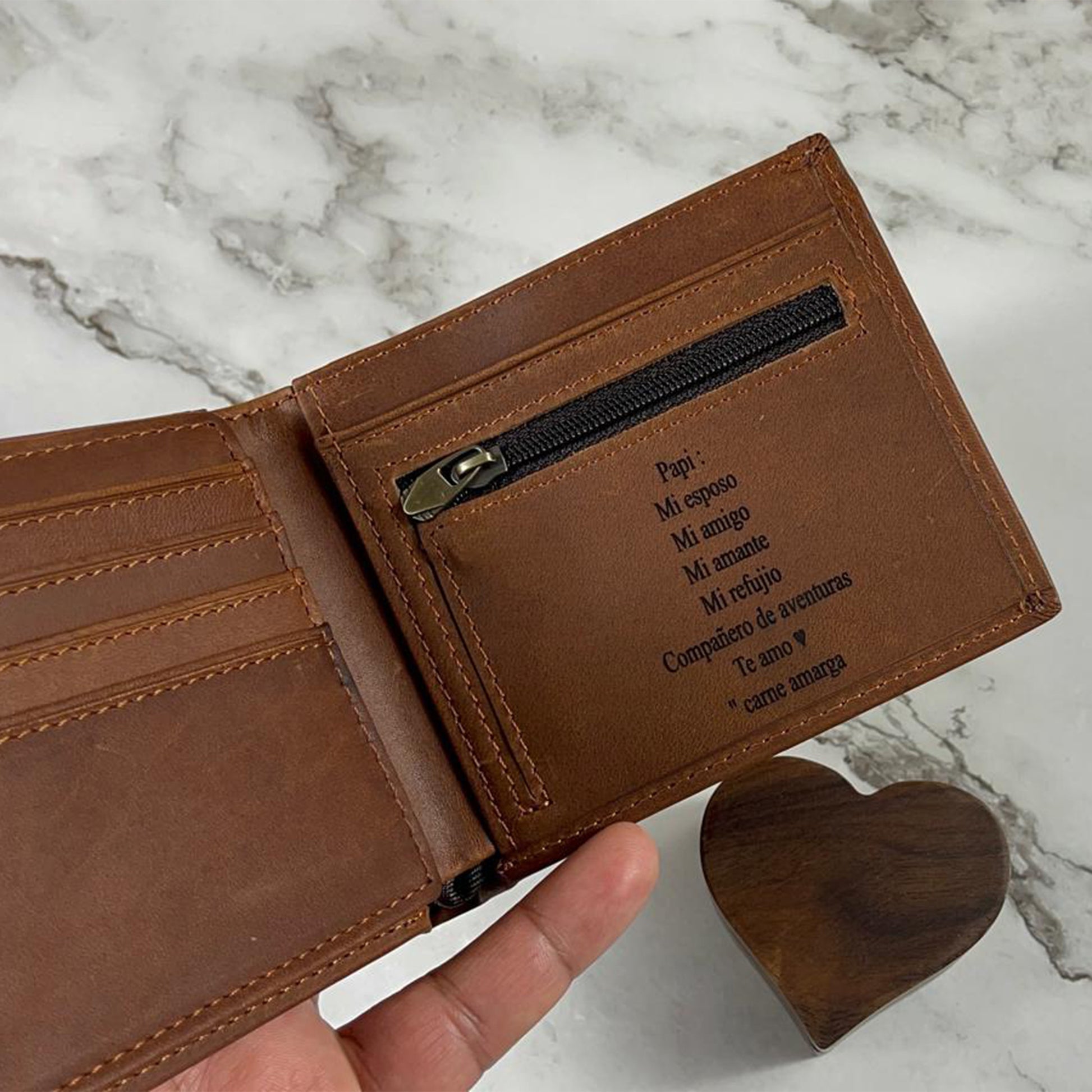 Handcrafted light brown leather wallet interior highlighting organized card slots, durable metal zipper hardware, and a personalized laser-etched sentimental message in Spanish.