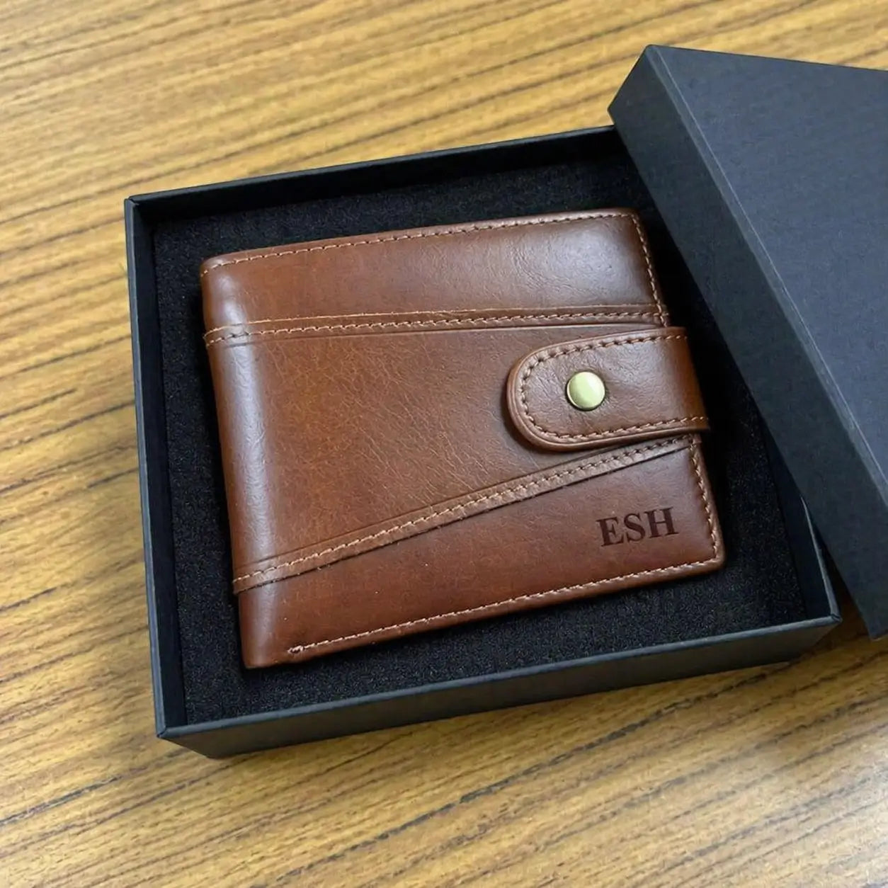 Custom engraved men's brown leather wallet with initials, handcrafted bifold design with decorative stitching in a professional gift box.