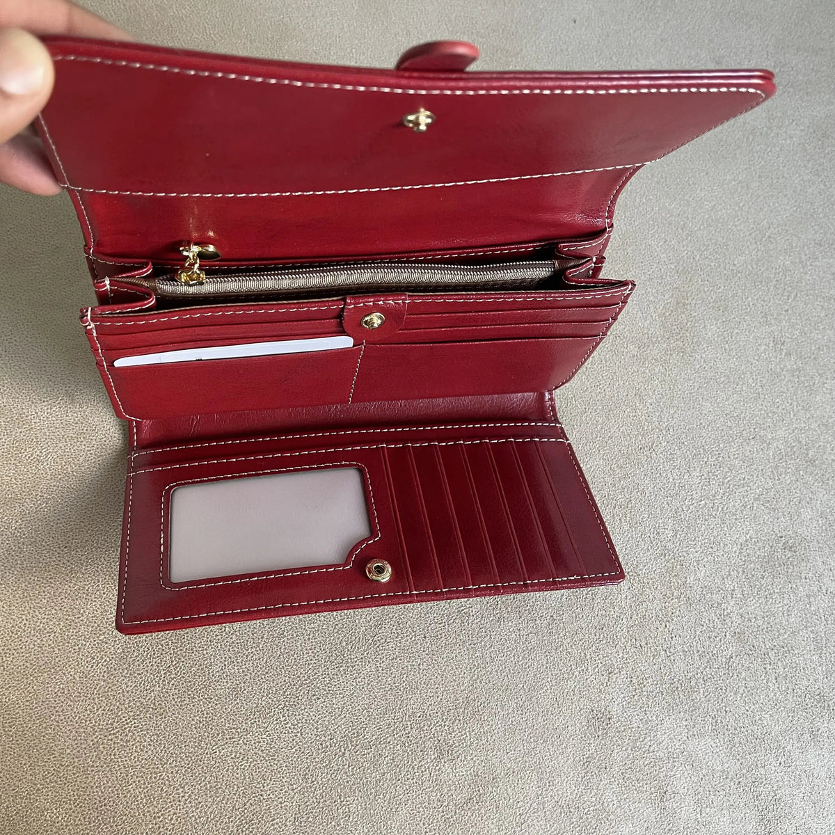 Open burgundy women’s wallet showing multiple card slots, ID window, zip coin pocket and spacious compartments